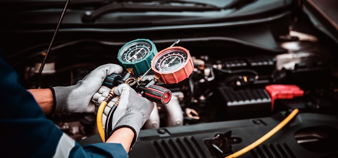 Close up hand of auto mechanic using measuring manifold gauge check the refrigerant and filling car air conditioner for fix and checking for repair service support maintenance and car insurance.